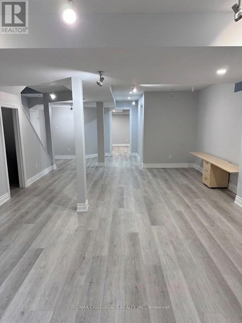 A spacious room with grey flooring and white walls, with a bench on the right side.