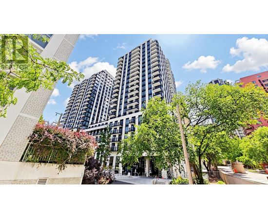 A modern building with a lot of windows and balconies is surrounded by trees and plants.