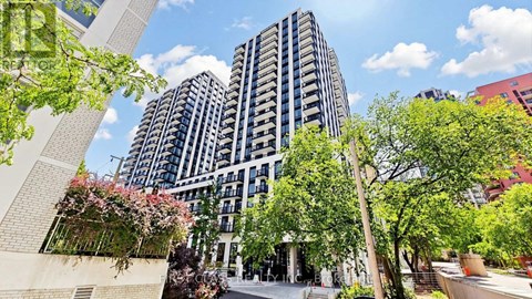 A modern building with a lot of windows and balconies is surrounded by trees and plants.