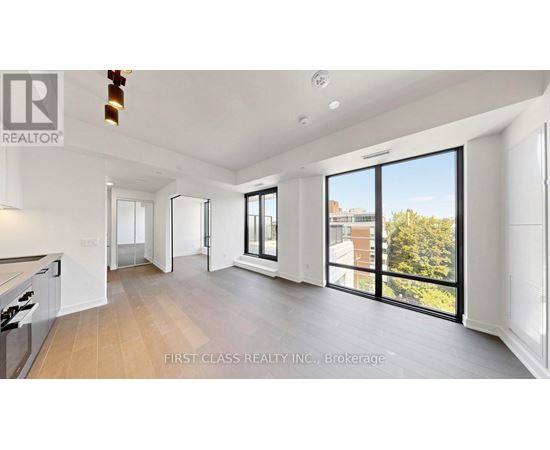 A spacious, well-lit living room with a kitchen area and sliding glass doors.