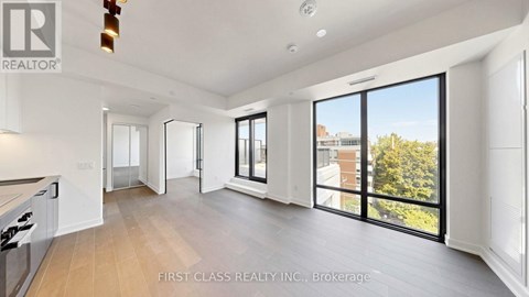 A spacious, well-lit living room with a kitchen area and sliding glass doors.
