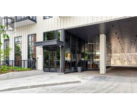 The entrance to a building with a glass door and a black railing.