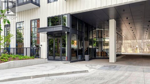 The entrance to a building with a glass door and a black railing.
