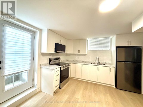 A kitchen with white cabinets and a black fridge.