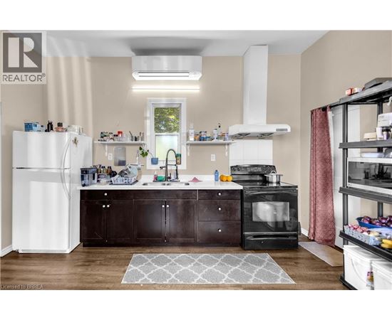 A kitchen with a white refrigerator, black cabinets, and a black stove top oven.