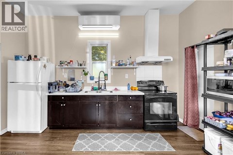 A kitchen with a white refrigerator, black cabinets, and a black stove top oven.