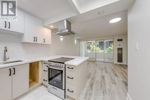 A modern kitchen with white cabinets and a black stove top oven.