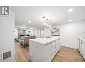 A well-lit, spacious kitchen with white cabinets and a dining area with a table set for four.