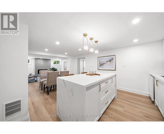 A well-lit, spacious kitchen with white cabinets and a dining area with a table set for four.