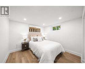 A bedroom with a white bed and a wooden floor.