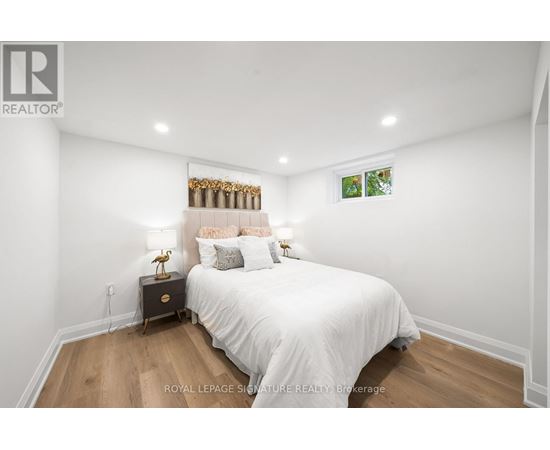 A bedroom with a white bed and a wooden floor.