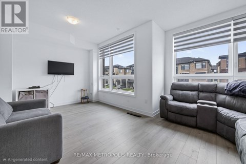 A living room with a grey couch and a flat screen TV mounted on the wall.