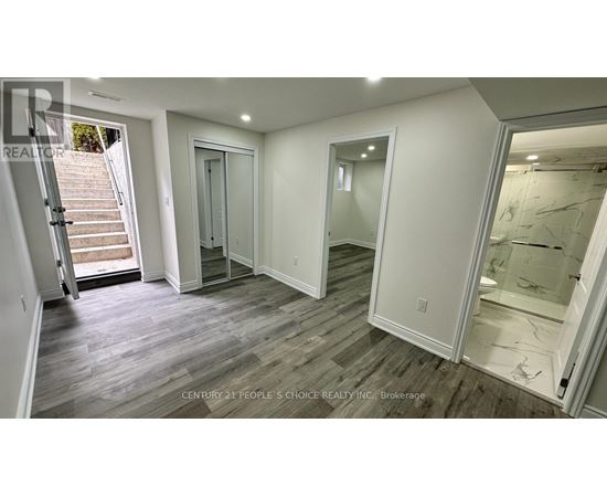 A spacious room with wooden flooring and white walls.