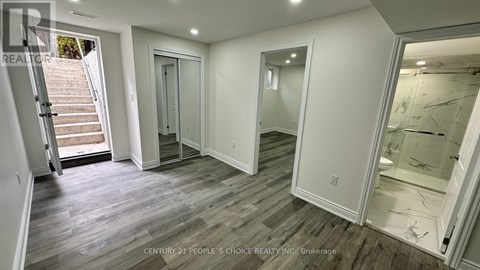 A spacious room with wooden flooring and white walls.