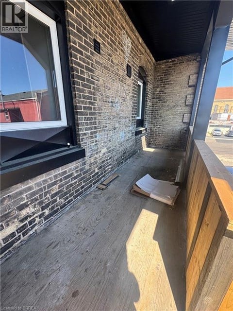 A balcony with a brick wall and wooden floor.