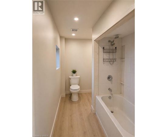 A white toilet sits in a bathroom next to a bathtub.