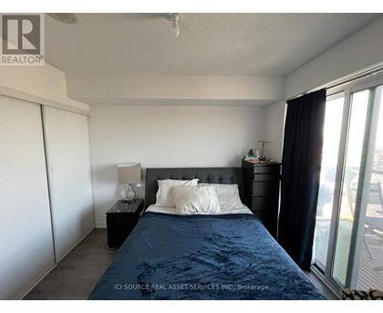 A bedroom with a bed, nightstand, and window.