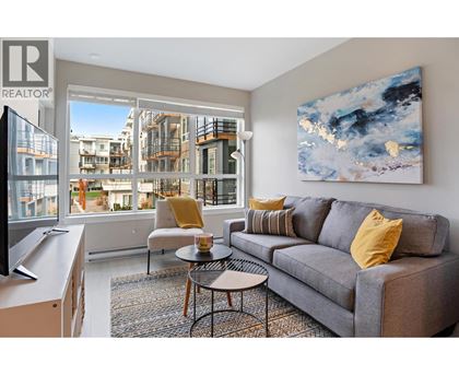 A living room with a grey couch and a painting on the wall.
