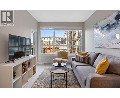 A living room with a grey couch, a black coffee table, a television, and a large window with a view of a building.