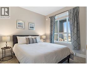 A bedroom with a large bed, two lamps, and pictures on the wall.