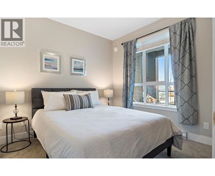 A bedroom with a large bed, two lamps, and pictures on the wall.