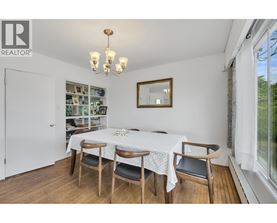 A dining room with a table set for two and a chandelier.