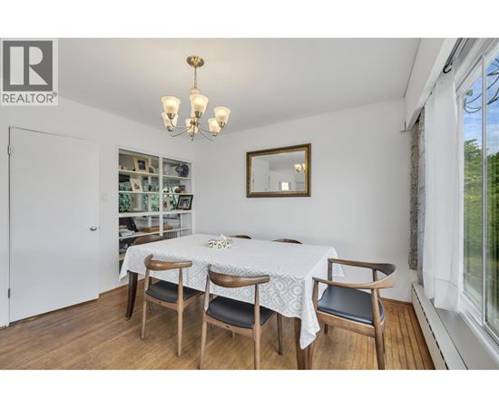 A dining room with a table set for two and a chandelier.