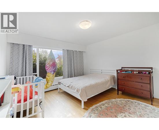 A bedroom with a white bed and a white dresser.