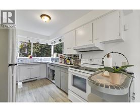 A well-lit kitchen with white appliances and cabinets.