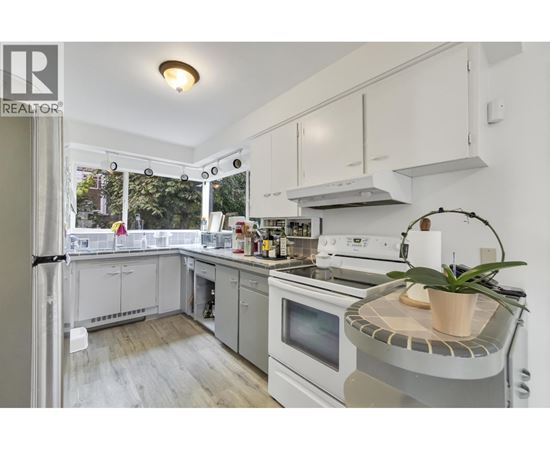 A well-lit kitchen with white appliances and cabinets.