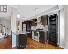 A modern kitchen with dark wood floors and stainless steel appliances.