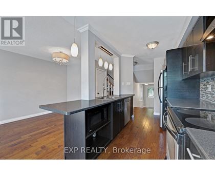 A kitchen with a black counter top and wooden floors.