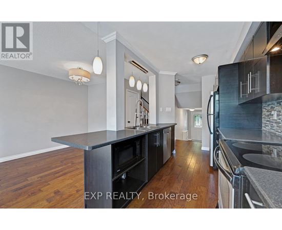 A kitchen with a black counter top and wooden floors.