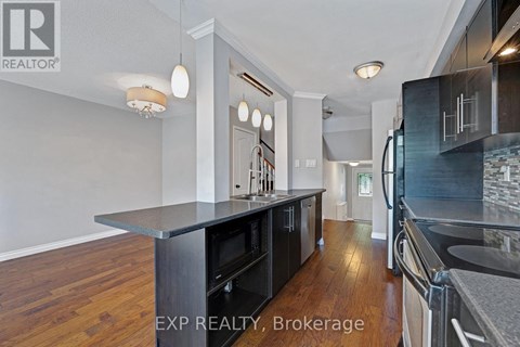 A kitchen with a black counter top and wooden floors.