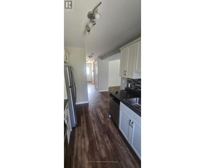 A kitchen with white cabinets and a wooden floor.