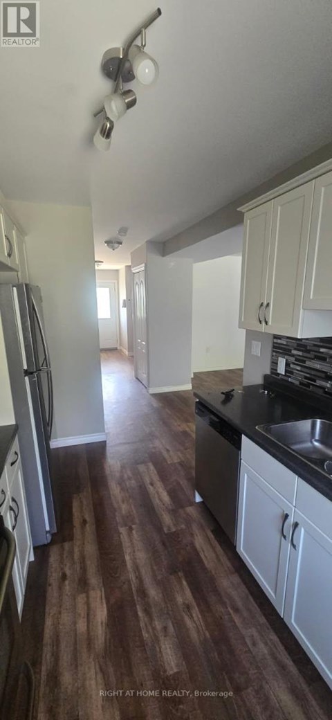 A kitchen with white cabinets and a wooden floor.