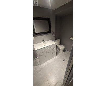 A bathroom with a toilet, sink, and mirror.