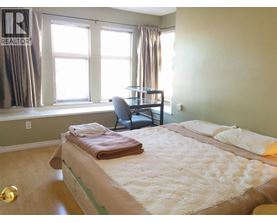A bedroom with a bed, chair, and window.
