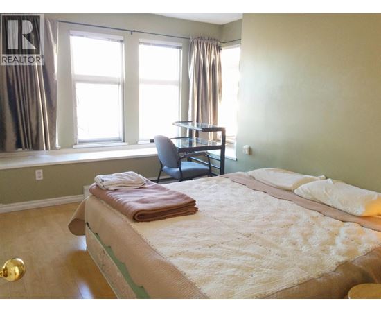 A bedroom with a bed, chair, and window.