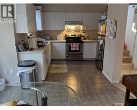 A kitchen with a refrigerator, oven, and sink.