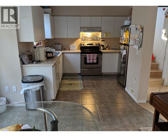 A kitchen with a refrigerator, oven, and sink.