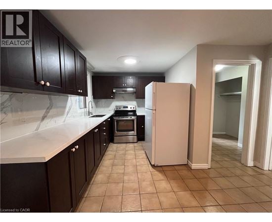 A kitchen with a refrigerator, oven, and cabinets.