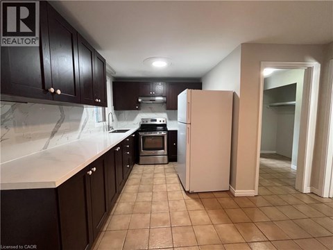A kitchen with a refrigerator, oven, and cabinets.