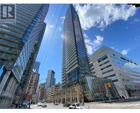 A tall glass building stands in the middle of a city intersection.