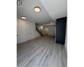 A room with a staircase and a black door.