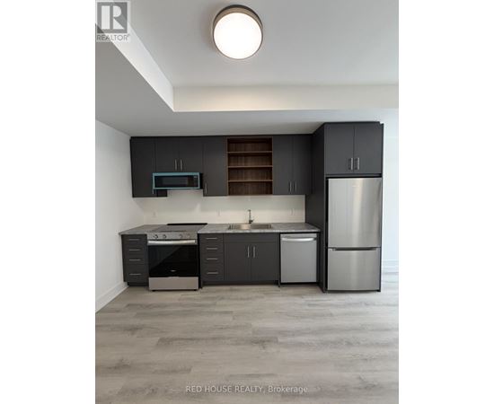 A modern kitchen with dark grey cabinets and stainless steel appliances.
