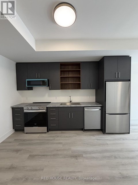 A modern kitchen with dark grey cabinets and stainless steel appliances.