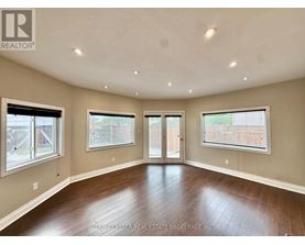 A spacious room with wood flooring and a sliding glass door.