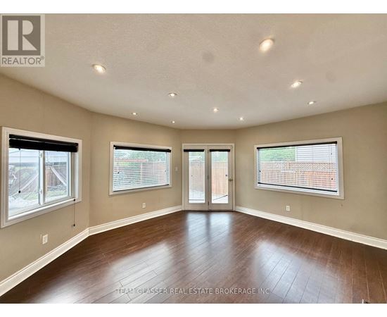 A spacious room with wood flooring and a sliding glass door.