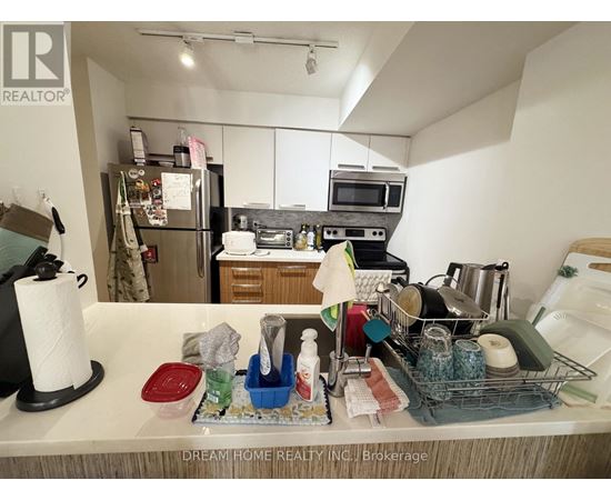 A kitchen counter with various items on it and a refrigerator in the background.